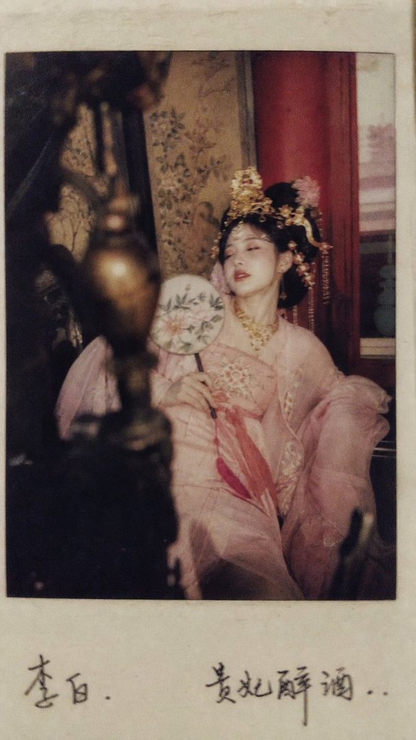 A photorealistic portrait of a young East Asian woman in traditional Chinese attire, holding a fan, with elaborate golden hair ornaments.