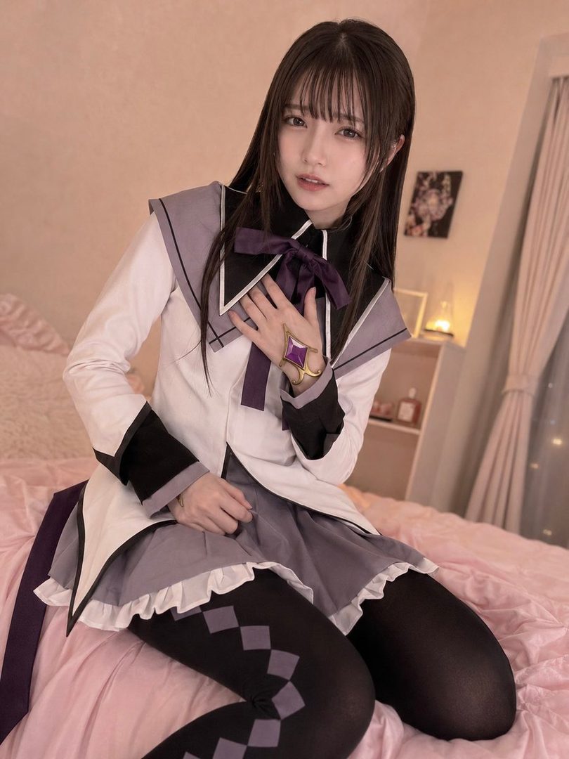 A young woman in a magical girl costume sits on a bed, posing for a photo.