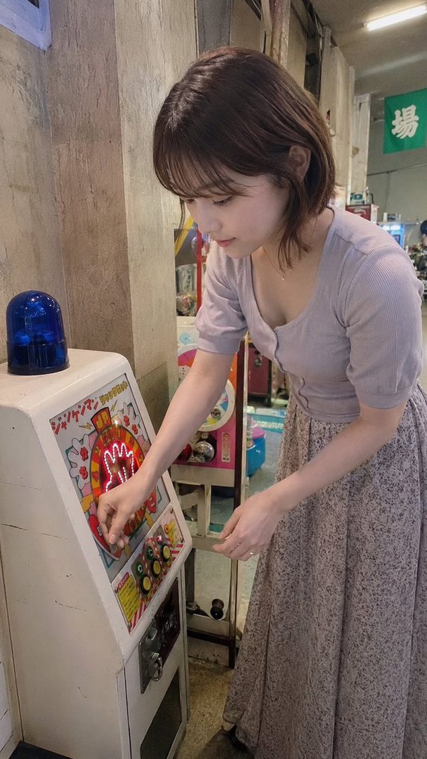 A young woman with short brown hair plays a vintage medal game machine in an arcade.