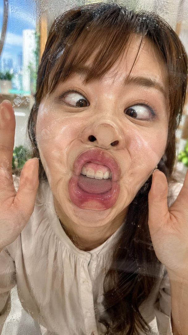 A woman makes a funny face by pressing her face against a glass surface, distorting her features.