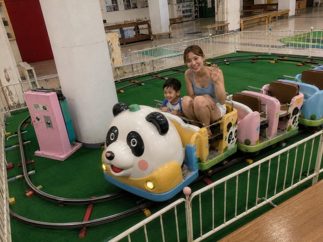 A young woman and a child ride a panda-themed amusement park train indoors.