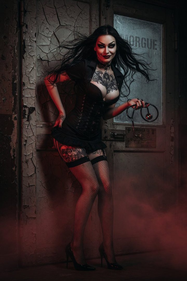 A gothic nurse with long black hair and dramatic makeup, wearing a corset, short skirt, and fishnet stockings, poses seductively with a stethoscope.