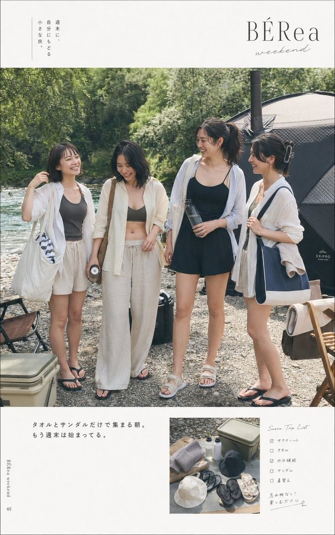 Four young women are enjoying a relaxed summer day by a river, dressed in casual linen outfits and sandals, with camping gear visible in the background.