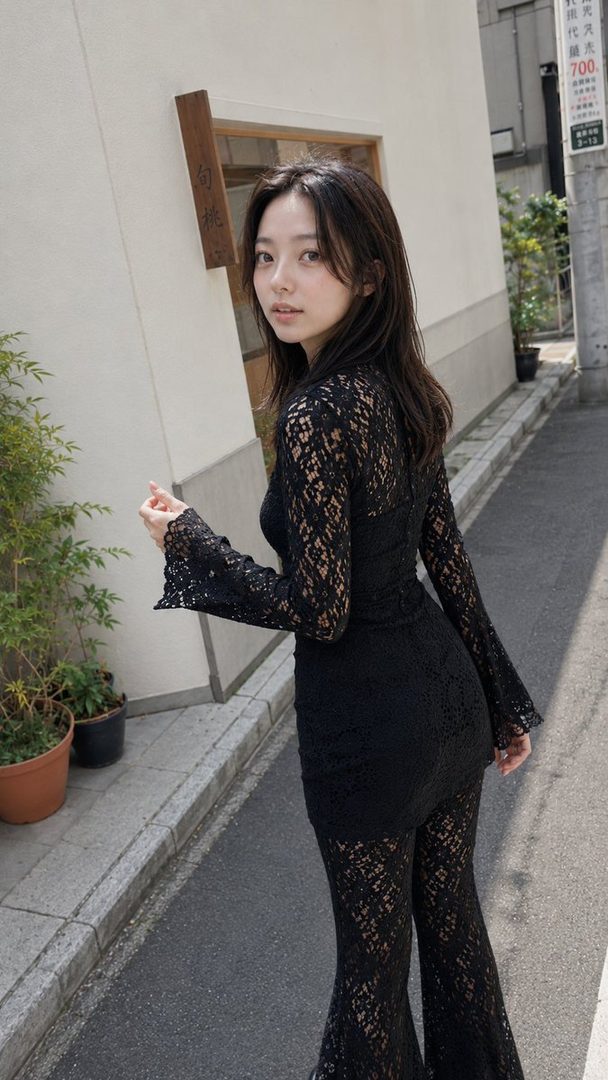 A young East Asian woman with long dark hair, wearing a black lace outfit, poses on a street.