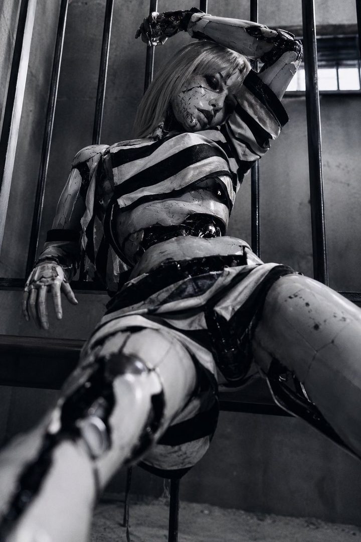 AI-generated portrait of a cyborg woman in a striped outfit, posing behind bars.