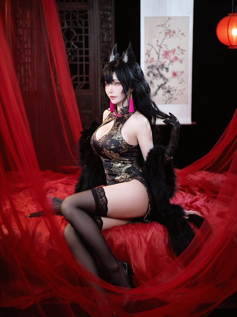 A woman in a black and gold cheongsam-style outfit with fox ears and a fur stole poses seductively on a red draped bed.