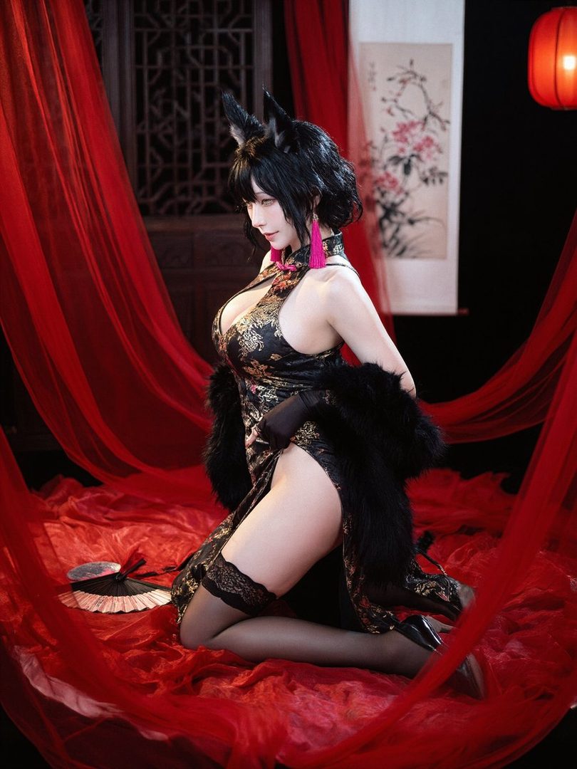 A woman in a black and gold cheongsam with fox ears and a fluffy stole poses suggestively indoors.