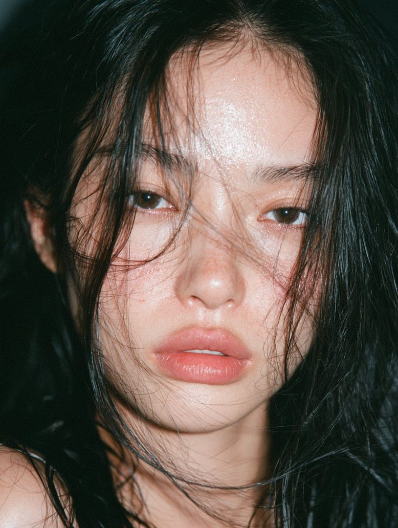 Close-up portrait of a young East Asian woman with long, dark, messy hair and a soft, natural makeup look.