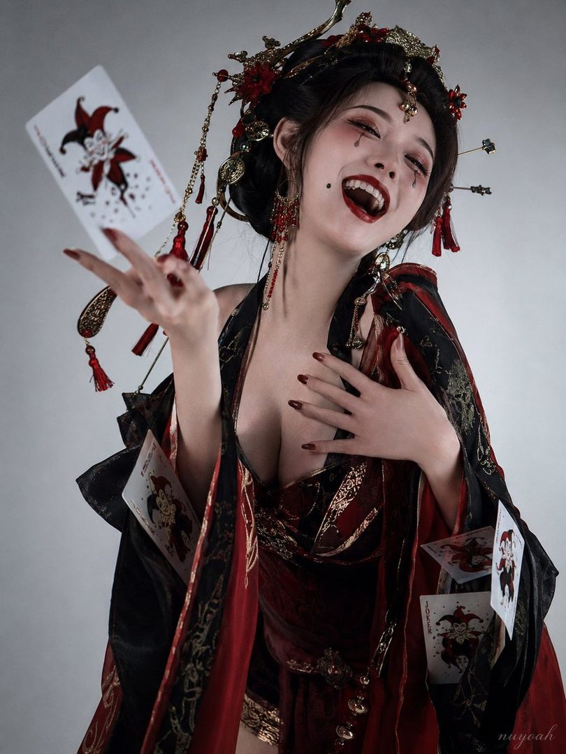 A woman in a red and black traditional Japanese-inspired outfit with joker cards, striking a playful pose.