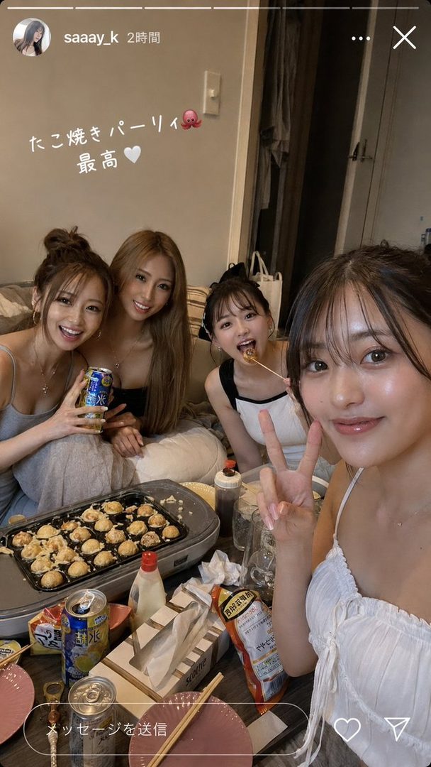 Four young women are enjoying a takoyaki party at home, with one taking a selfie while another eats takoyaki.