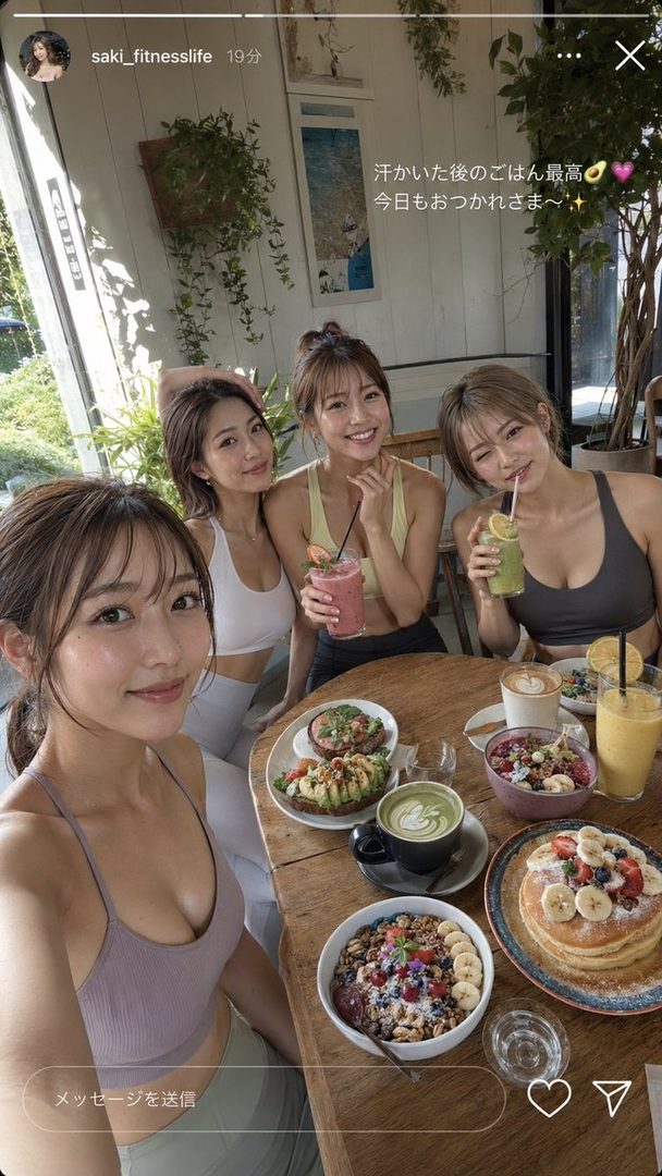 Four smiling women in sports bras are enjoying a healthy meal and drinks at a cafe, with various dishes like pancakes, acai bowls, and avocado toast on the table.