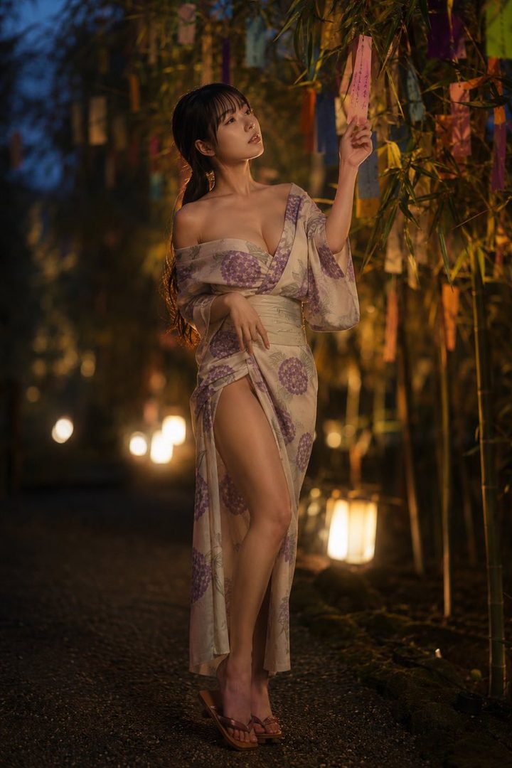 A young woman in a traditional Japanese yukata stands outdoors at night, with bamboo and lanterns in the background.