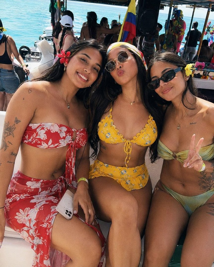 Three young women in bikinis posing on a boat in the Caribbean Sea.