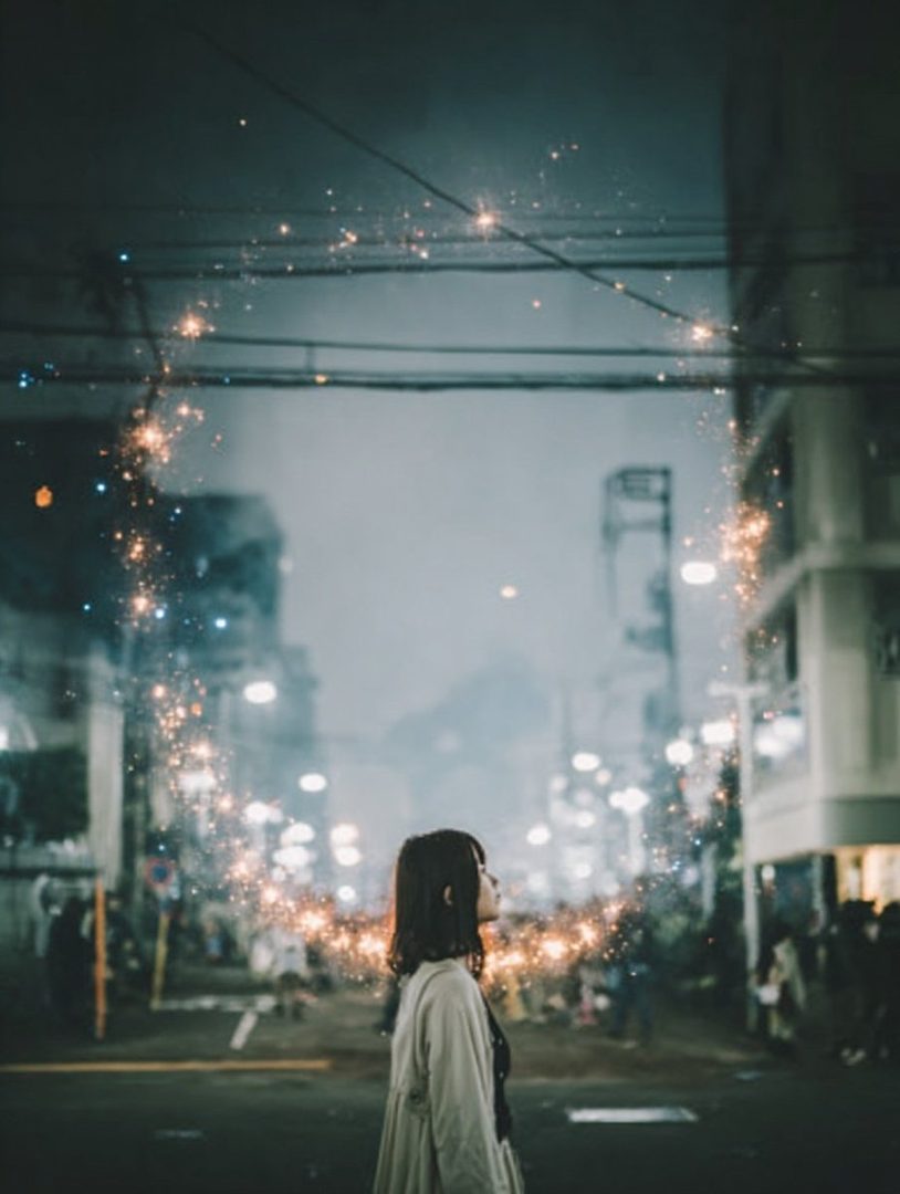 A young woman stands on a city street at night, looking up at a circular frame of sparkling lights.