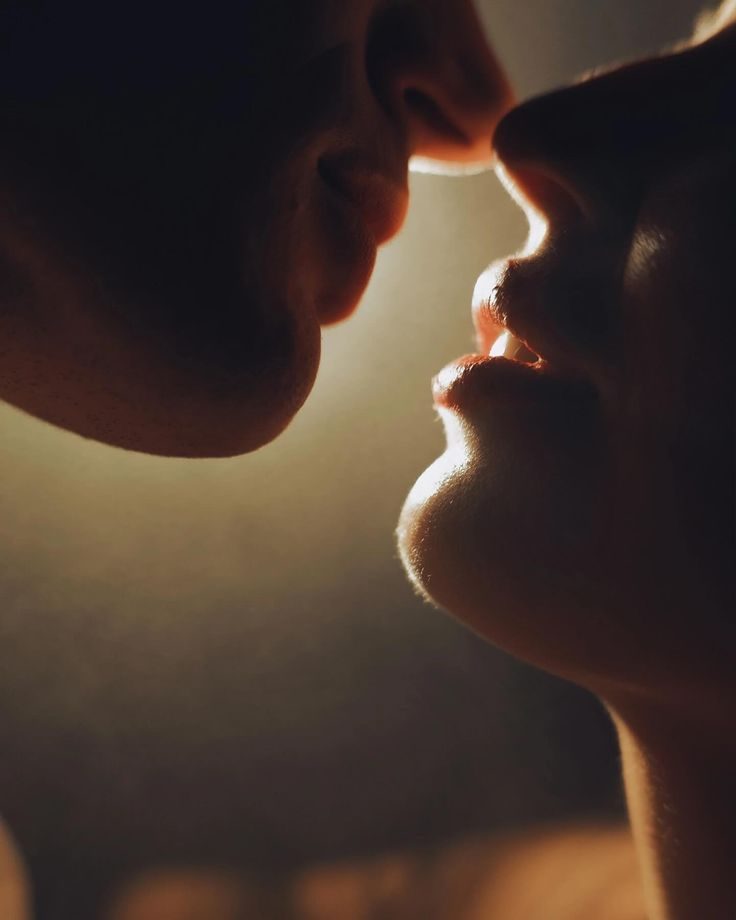 Close-up of two people kissing, with soft lighting highlighting their faces.