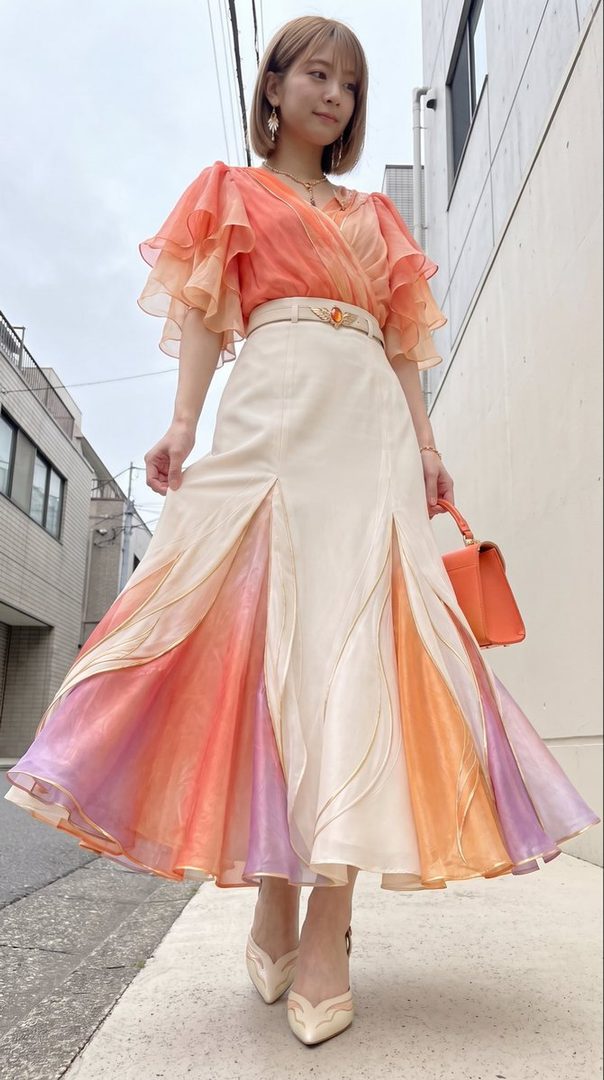 A Japanese woman in a flowing ombre dress and heels poses outdoors.