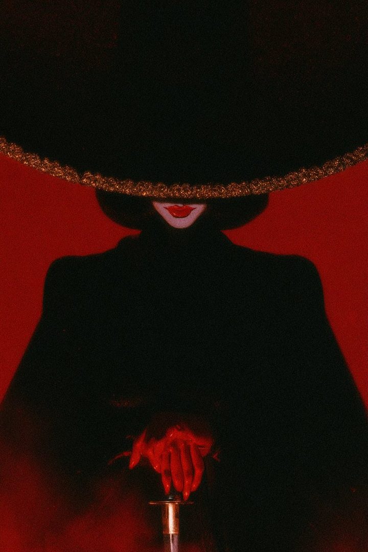 A person in a black outfit and a large black hat with a gold trim, holding a golden object, against a red background.
