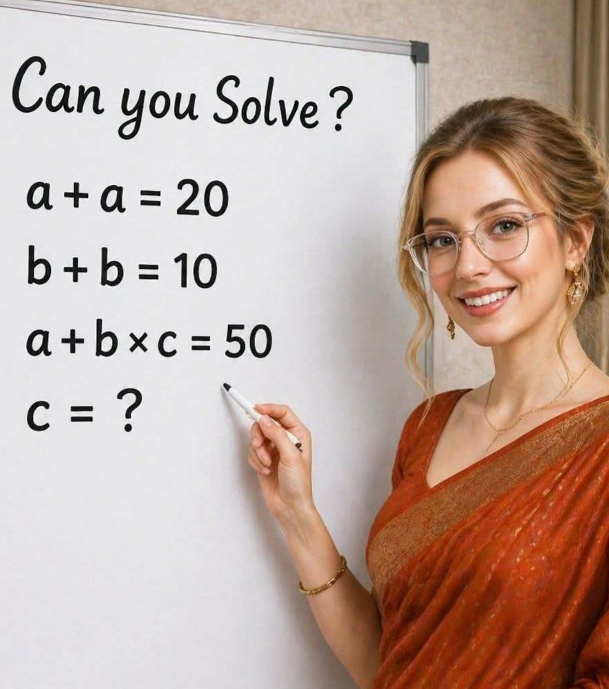 A smiling woman with blonde hair and glasses, wearing an orange saree, stands in front of a whiteboard with a math problem.