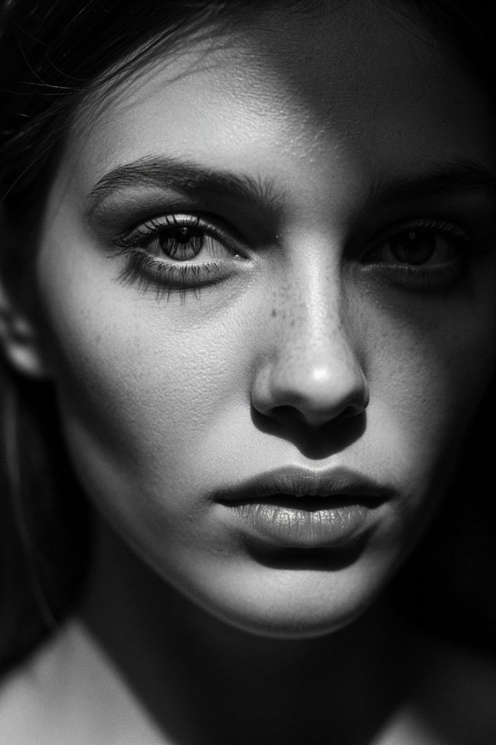 Extreme close-up black and white portrait of a young woman's face with dramatic lighting.