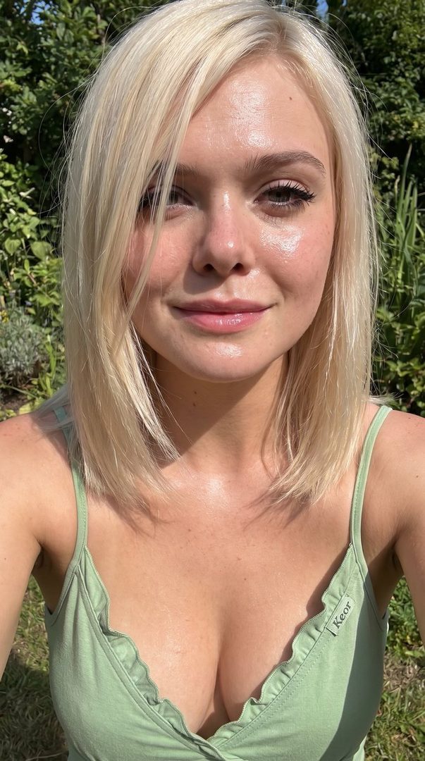 Close-up selfie of a young woman with blonde hair and a green top, smiling outdoors.