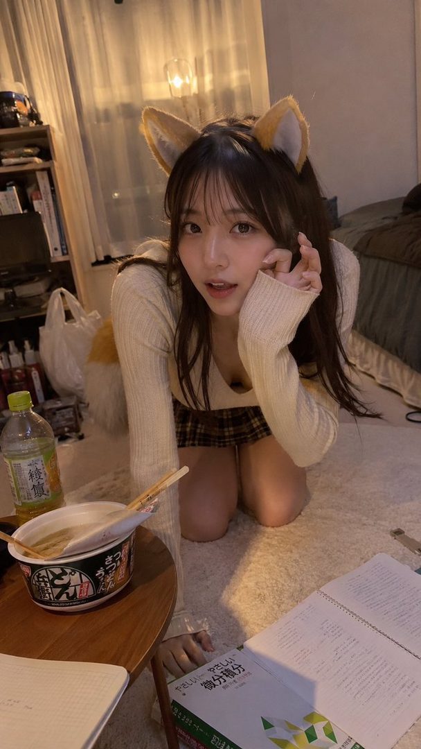 A young East Asian woman with fox ears and a tail, wearing a sweater and plaid skirt, kneels indoors with a bowl of noodles and books.