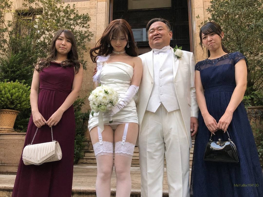 A bride in a short white wedding dress and thigh-high stockings poses with a groom in a white suit and two bridesmaids in dark dresses.