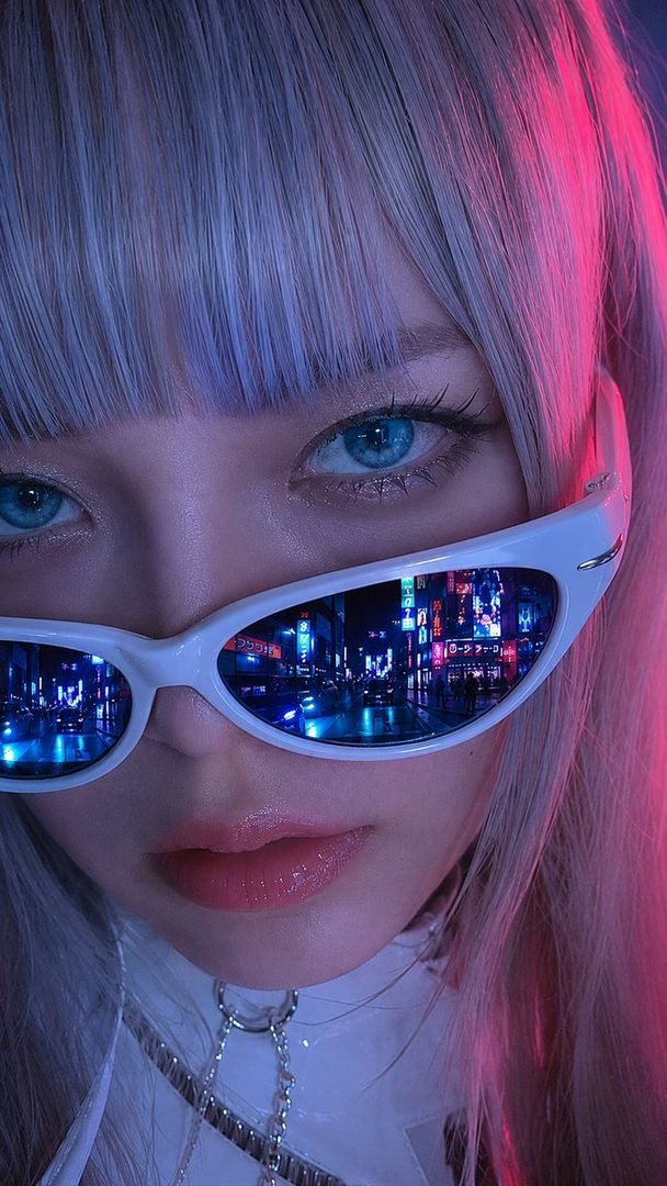 A close-up portrait of a woman with silver hair and blue eyes, wearing white futuristic sunglasses that reflect a neon city street.
