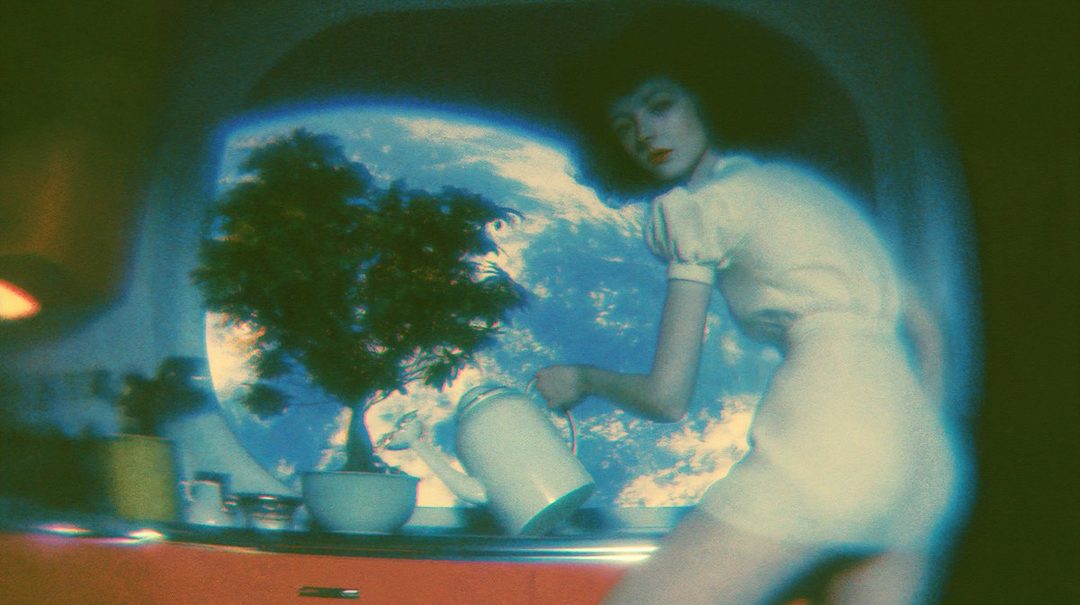 A woman with dark short hair, wearing a white dress, watering a plant in front of a large window showing a view of Earth from space. The image has a dreamy, cinematic aesthetic.
