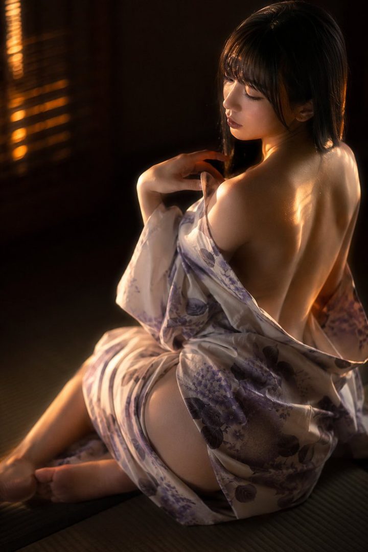 A woman in a yukata, with her back to the camera, bathed in warm light.