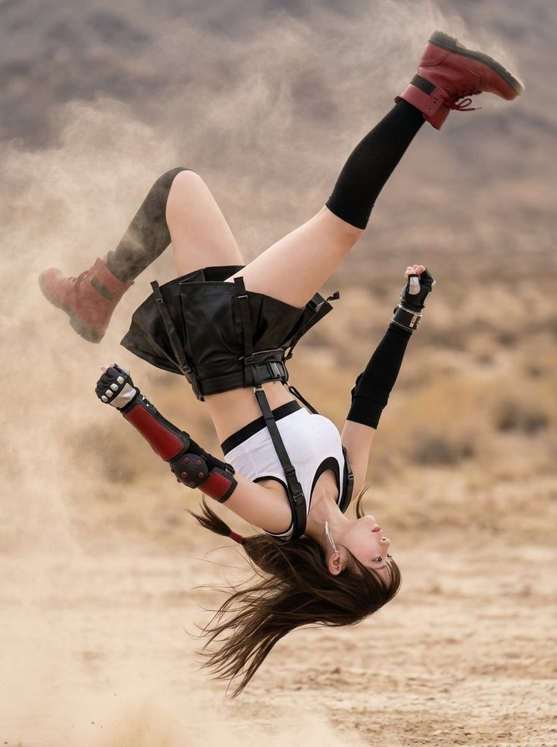 A cosplayer dressed as Tifa Lockhart from Final Fantasy VII is captured mid-air performing a dynamic kick in a dusty desert landscape.