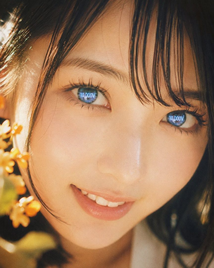 A close-up portrait of a smiling woman with dark hair and bangs, featuring glowing blue eyes with '10,000V' text, set against a warm, golden-hour backdrop with soft-focus flowers.
