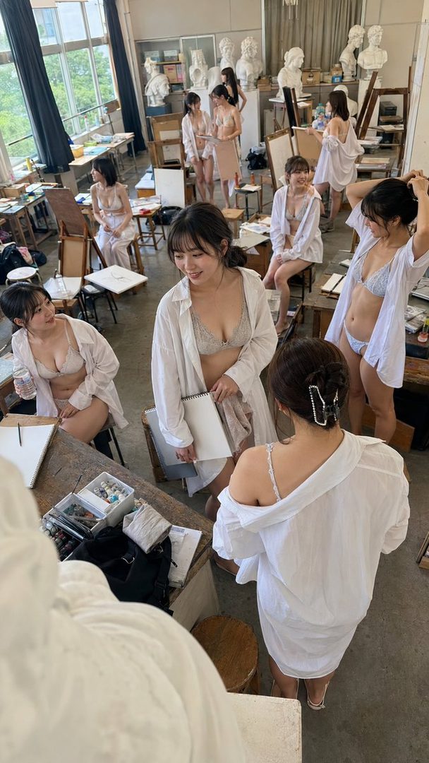 Group of young women posing in an art studio wearing lingerie and open white shirts during a life drawing session.