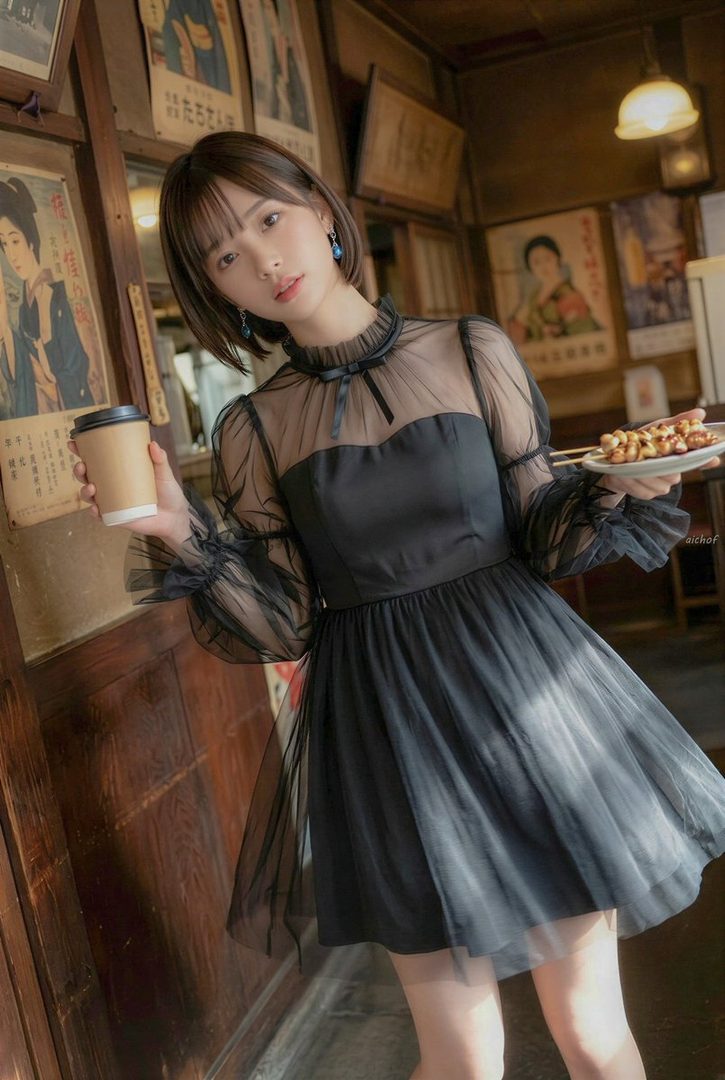 Young woman in a black sheer dress holding coffee and grilled skewers inside a vintage Japanese cafe with wooden walls and posters.