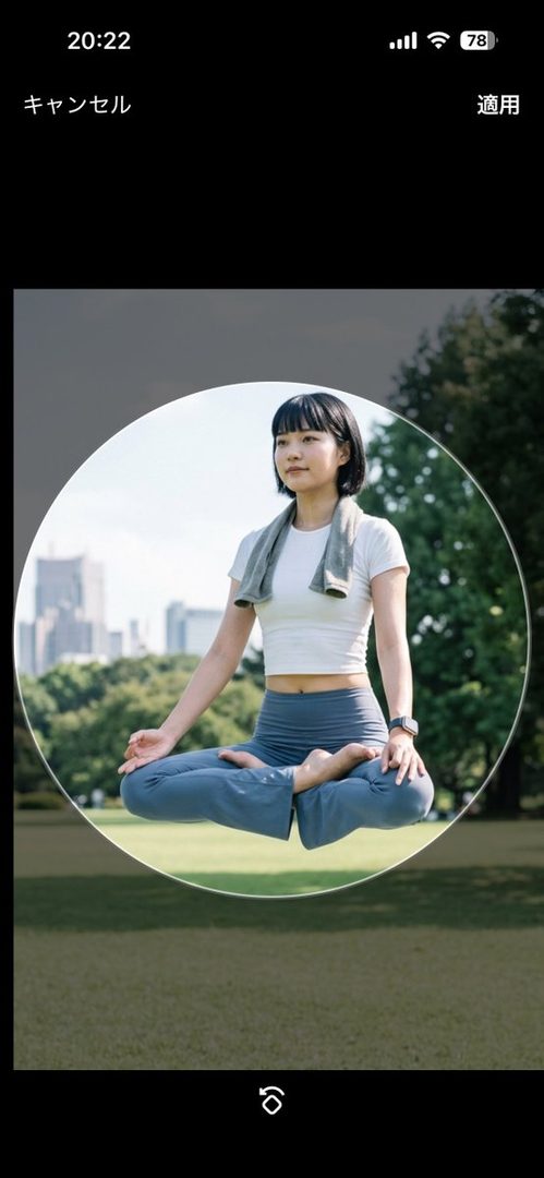 A woman with black bob hair meditates in a park, wearing a white crop top and blue yoga pants, with a towel around her neck.
