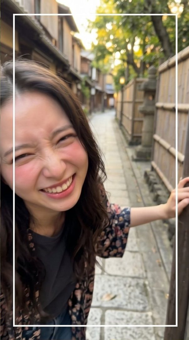 A young woman with long brown hair smiles playfully at the camera while standing on a cobblestone street lined with traditional Japanese buildings.