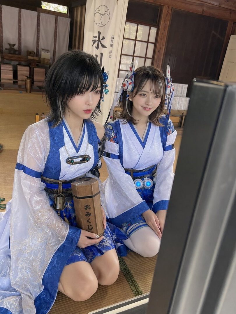 Two young women in blue and white miko-style cosplay outfits kneeling together in a traditional Japanese tatami room.