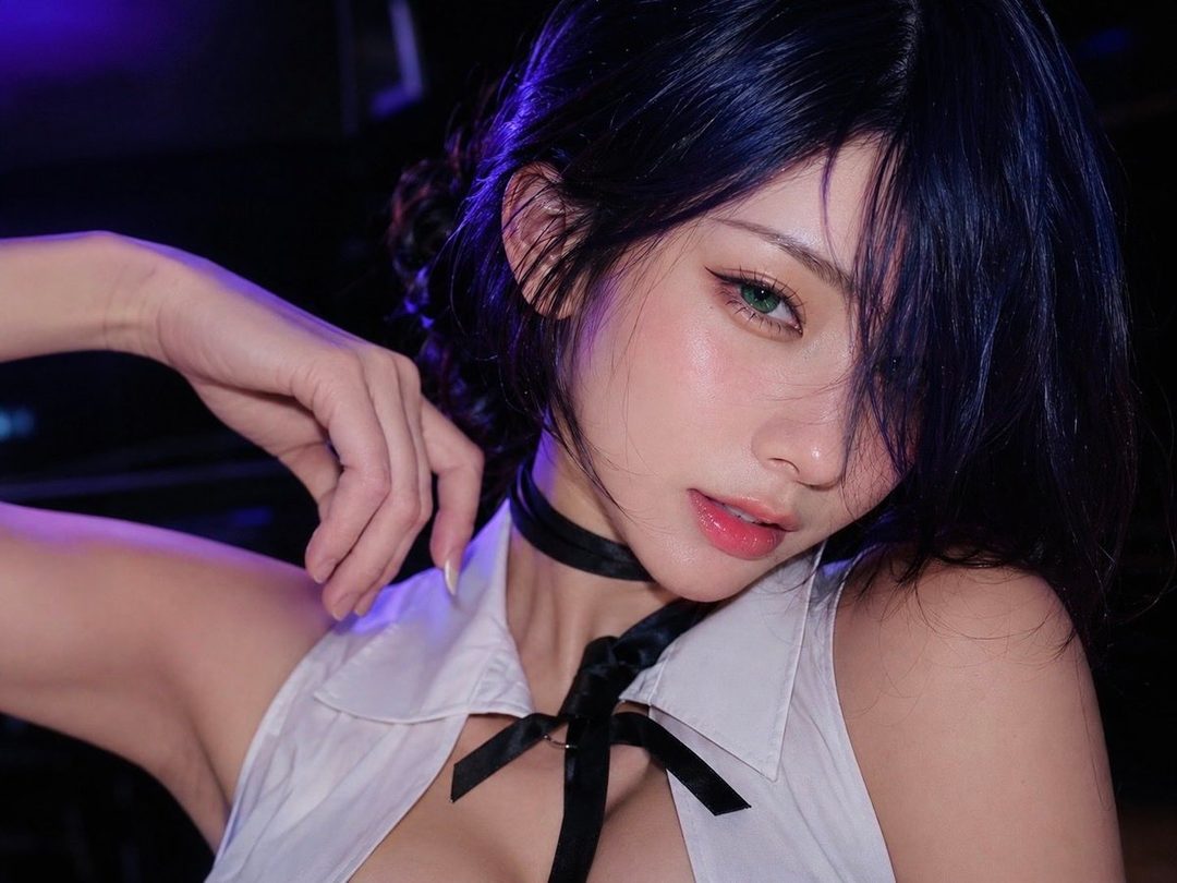 Close-up beauty portrait of a young woman with dark hair cosplaying as Reze, wearing a white sleeveless collared top with black ribbon tie under dramatic purple lighting.