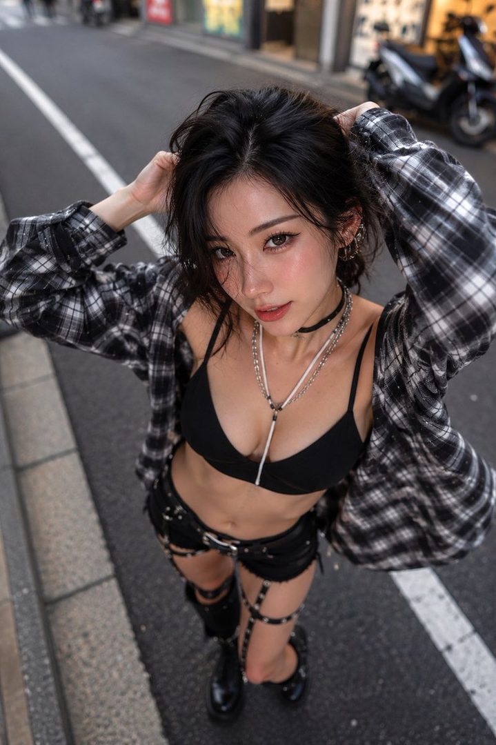 Young East Asian woman with long black hair posing confidently on an urban street in an open plaid shirt over a black crop top and chain-detailed shorts.