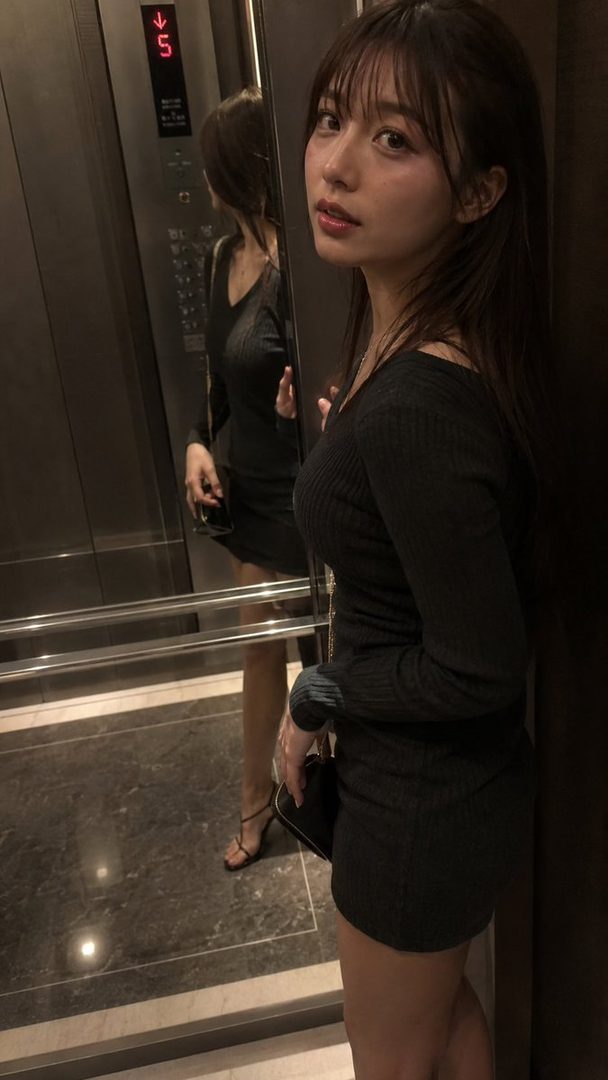 Young East Asian woman in a tight black mini dress posing for a mirror selfie inside an elevator at night.