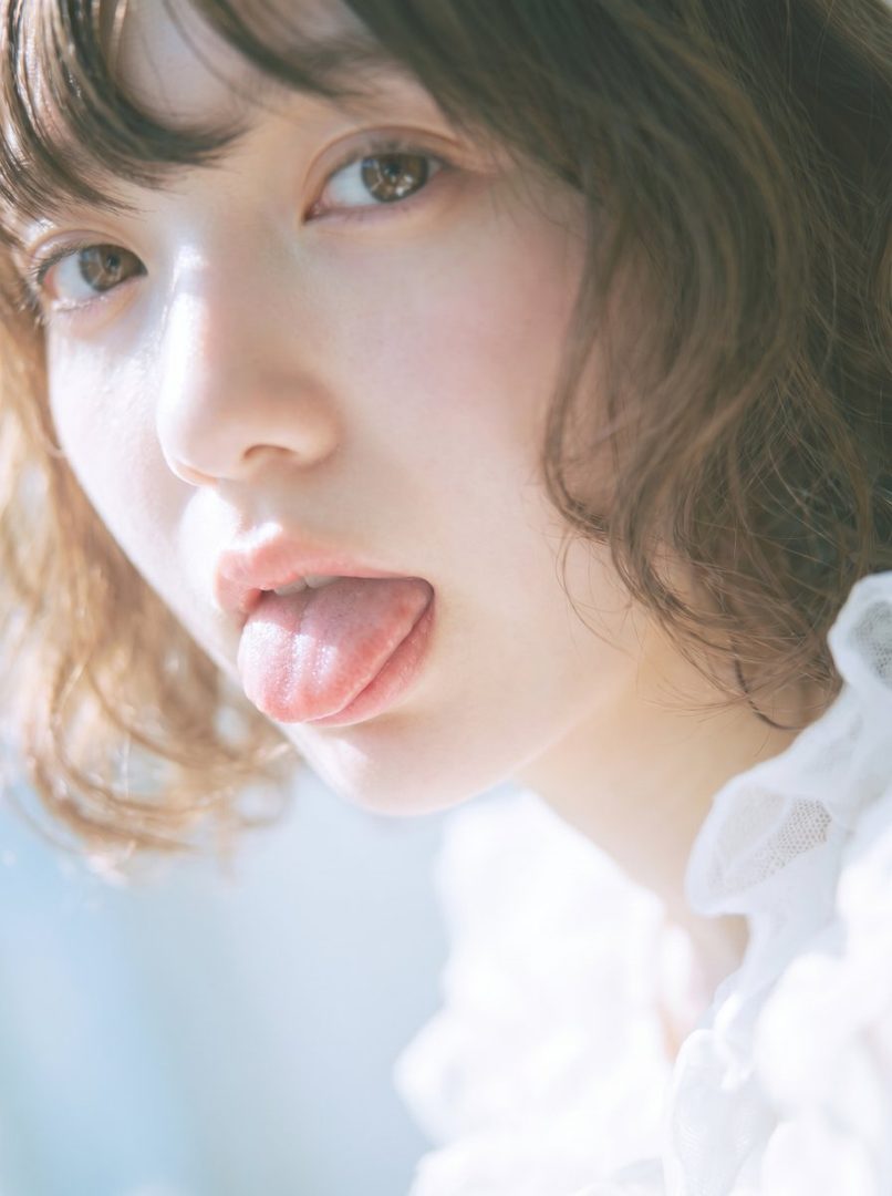 A close-up portrait of a woman with short brown hair sticking her tongue out playfully.