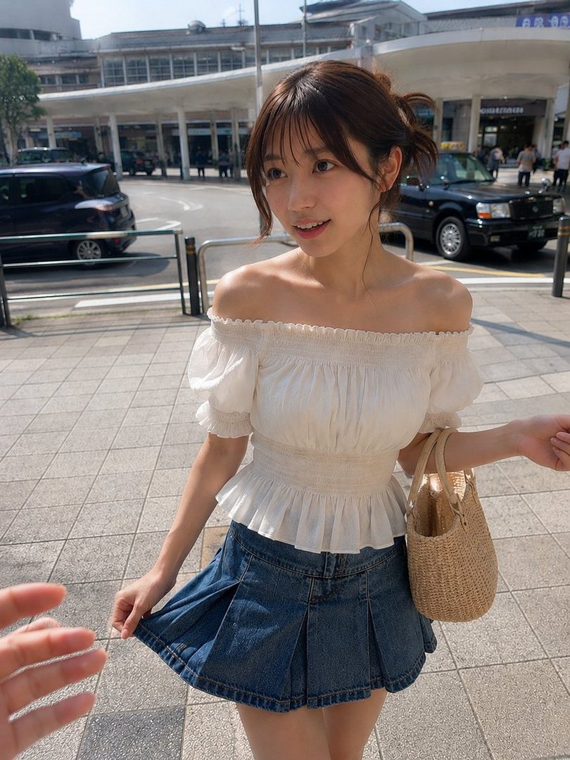 A young woman with brown hair and bangs, wearing a white off-shoulder blouse and a denim pleated skirt, stands on a city street during the daytime.