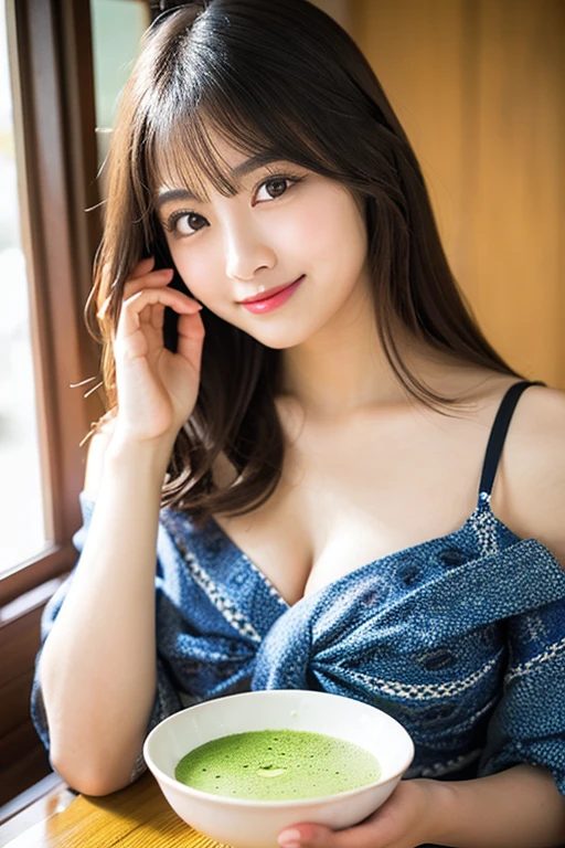 A beautiful East Asian woman with long brown hair and bangs, wearing a blue kimono-style top, holds a bowl of green matcha tea indoors.