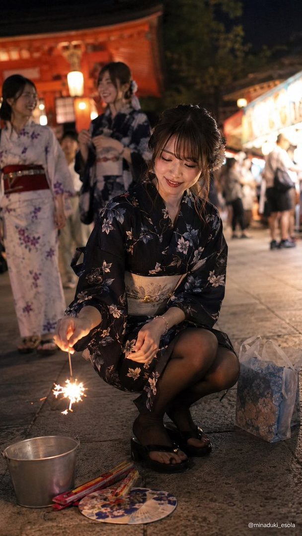 A Japanese woman in a dark yukata crouches down holding a sparkler at night, with other women in yukatas in the background.
