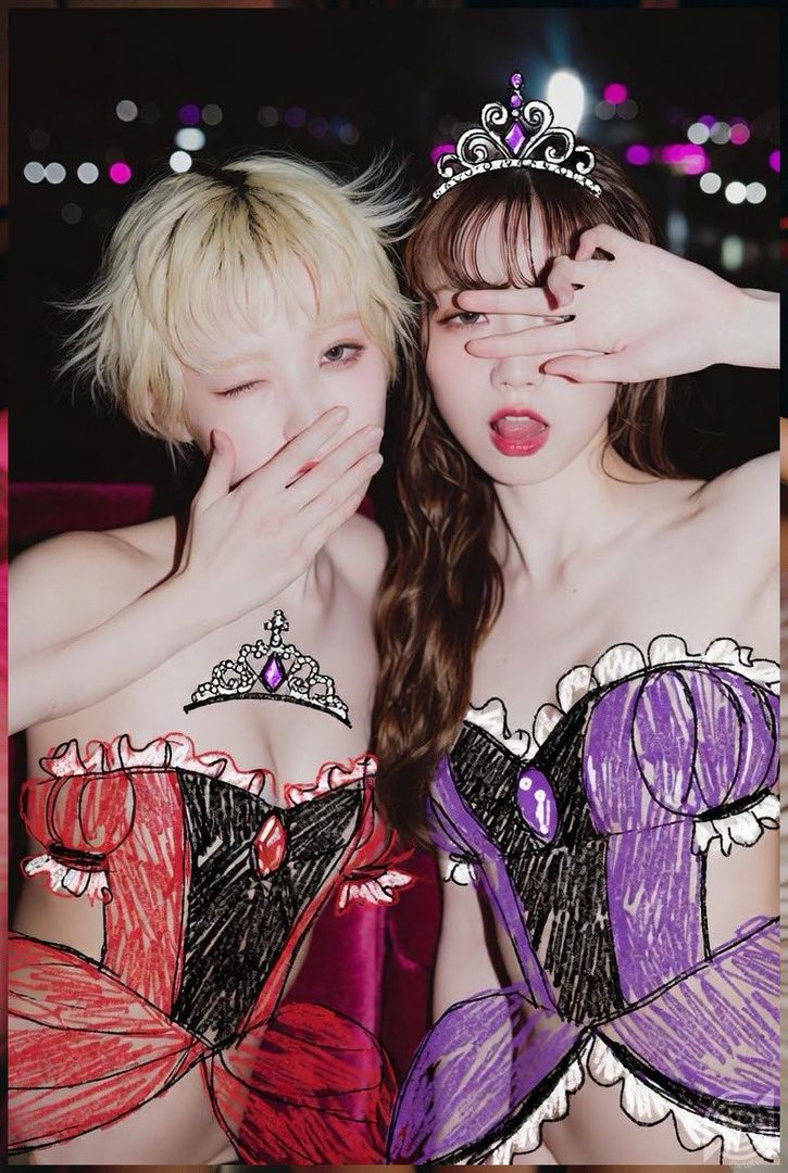 Two women with drawn-on dresses and tiaras pose playfully against a blurred night background.