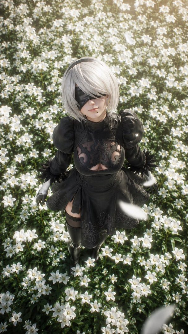 A woman cosplaying as 2B from Nier Automata stands in a field of white flowers, looking up at the viewer.
