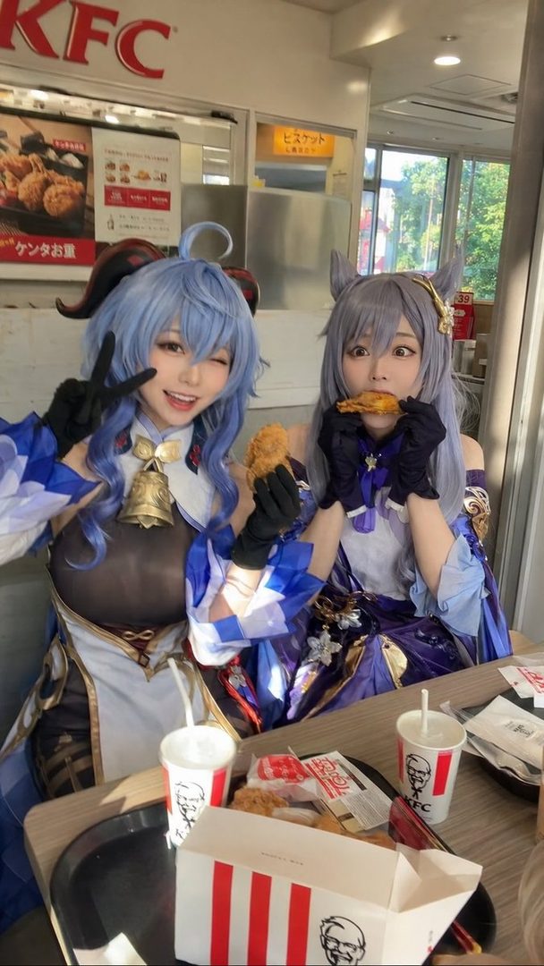 Two cosplayers dressed as Genshin Impact characters Ganyu and Keqing are eating fried chicken at KFC.