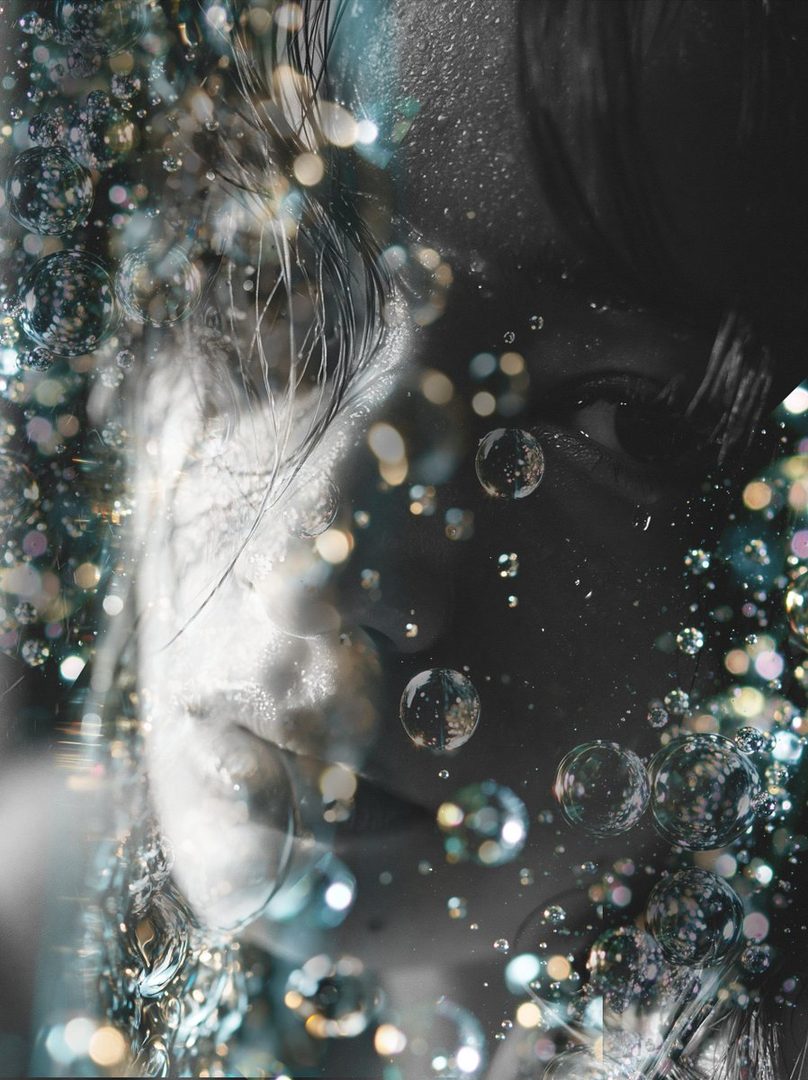A close-up portrait of a person with dark hair, surrounded by sparkling bubbles and bokeh lights, creating a dreamy and ethereal effect.
