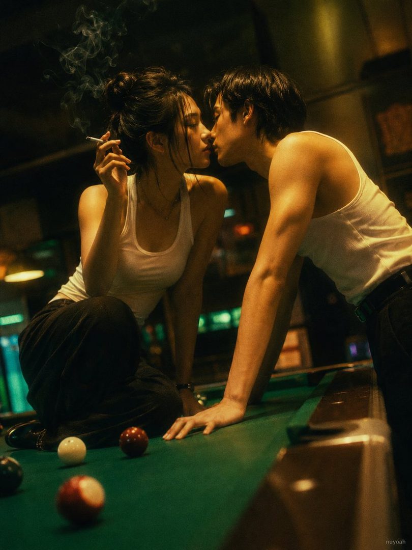 A couple in white tank tops and dark pants are about to kiss over a green pool table in a dimly lit room, with the woman holding a lit cigarette.