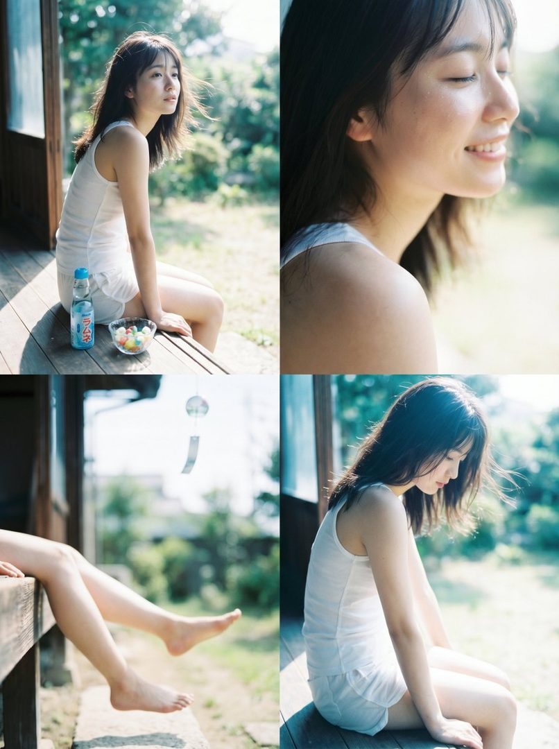 A young woman with long brown hair sits on a wooden porch, enjoying a summer day with a bottle of ramune and a bowl of candy.