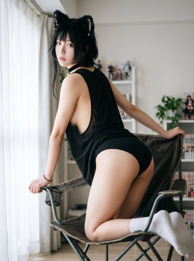 A young woman with black hair and cat ears kneels on a chair by a window, wearing a black tank top and black underwear.